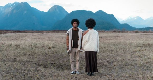 Boho Chic - An Afro-Haired Man and Woman Standing on a Grassy Field