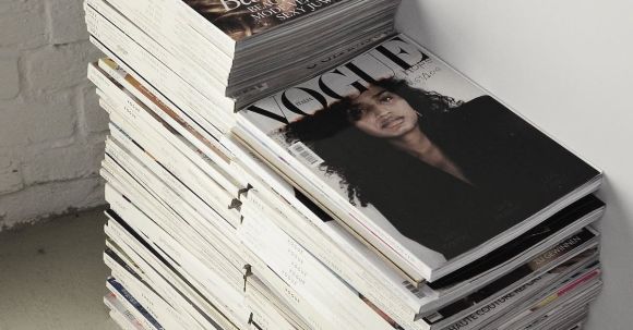 Fashion Collection - High angle many fashion magazines stacked on floor against white brick wall in studio