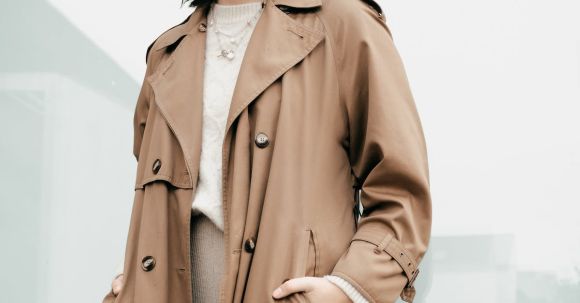 Chic Outerwear - Low angle of confident stylish young female with dark hair in trendy coat standing on street with hands in pockets and looking at camera